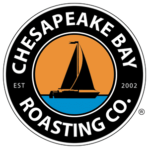 "CHESAPEAKE BAY ROASTING CO. EST 2002" written in white lettering around a circle with black background; center of logo has black sailboat on orange sky and blue water (cartoon image) with small reserved logo to right